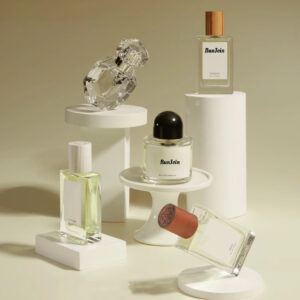 Assorted perfume bottles and caps displayed on white pedestals.