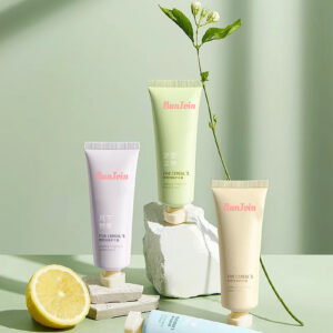 Pastel hand and foot care tubes beside a lemon and a leafy stem.