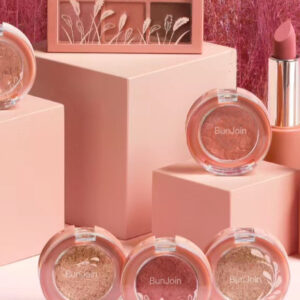 Pink lipsticks, lip gloss tubes and blush compacts on pink display blocks.