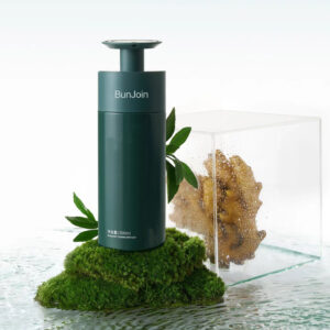 Dark green BunJoin conditioner pump bottle displayed on moss beside botanical material.