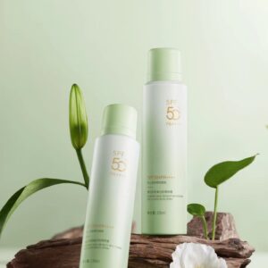 Two pale green sunscreen containers beside leaves and a white flower.