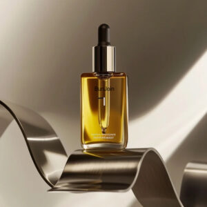 Amber serum dropper bottle displayed on metallic ribbon.